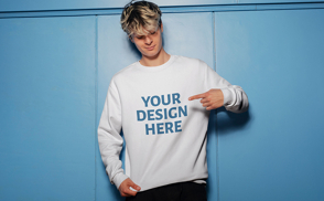 Man with blue walls pointing to sweatshirt mockup