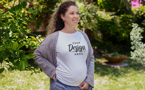 Happy pregnant woman in garden with t-shirt mockup