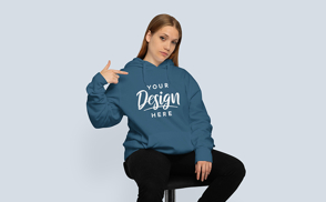 Girl sitting and pointing hoodie mockup | Start Editing Online