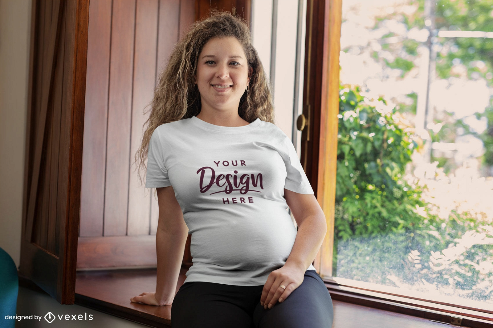 Modelo grávida sentada perto da maquete de camiseta da janela